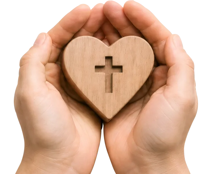 Zwei Hände halten ein Holzherz mit eingeschnittenem Kreuz